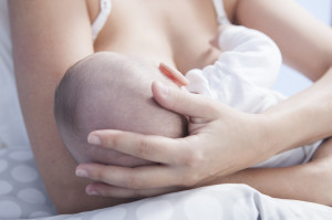 Mother holds her baby head while he is breastfed. Closeup