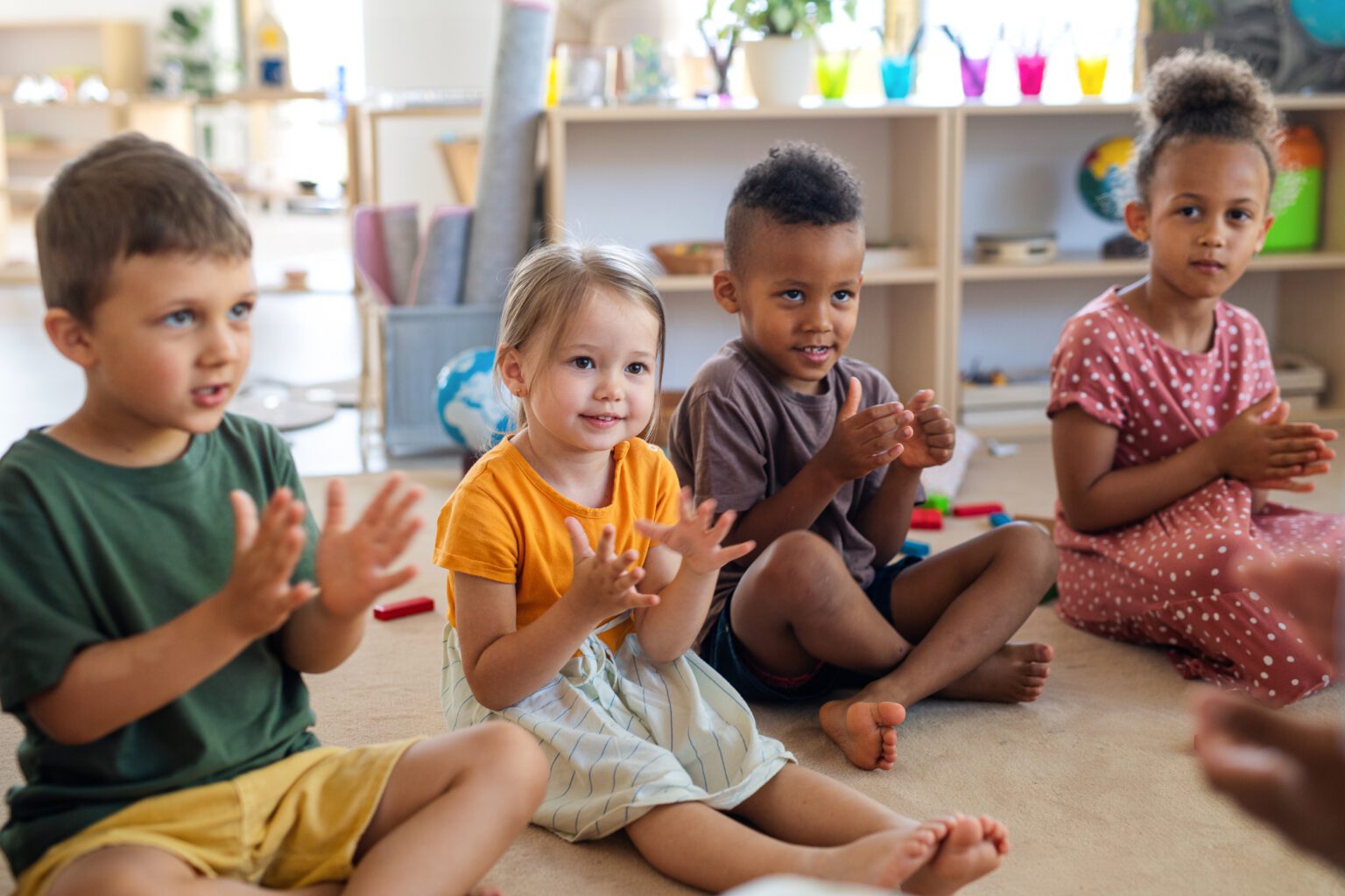Group of young children sitting on floor in school.