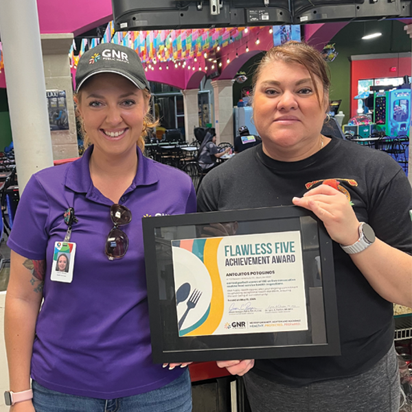 Restaurant staff and GNR Public Health inspector pose with a framed and signed Flawless Five Achievement Award certificate.