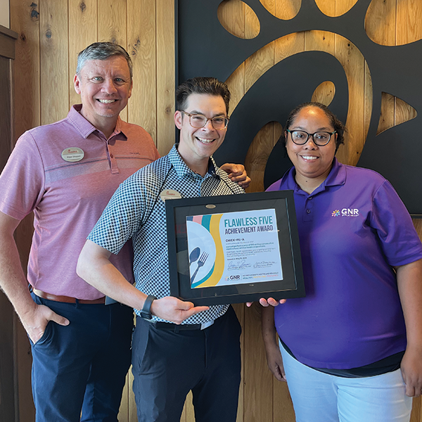 Restaurant staff and GNR Public Health inspector pose with a framed and signed Flawless Five Achievement Award certificate.