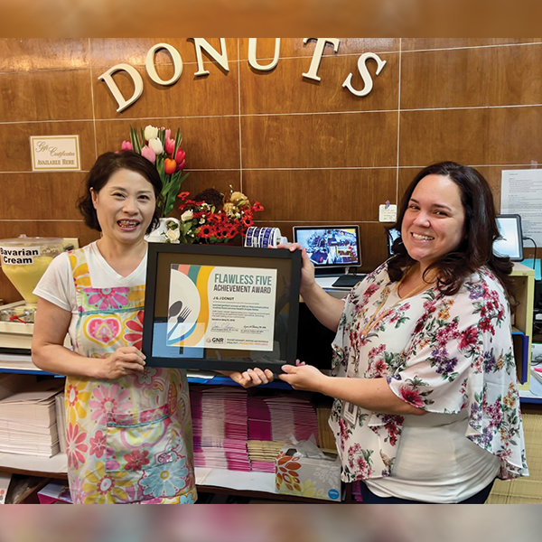 Restaurant staff poses with a framed and signed Flawless Five Achievement Award certificate.