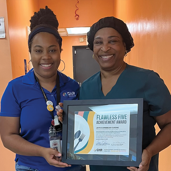 Restaurant staff and GNR Public Health inspector pose with a framed and signed Flawless Five Achievement Award certificate.