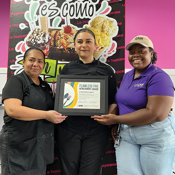 Restaurant staff and GNR Public Health inspector pose with a framed and signed Flawless Five Achievement Award certificate.