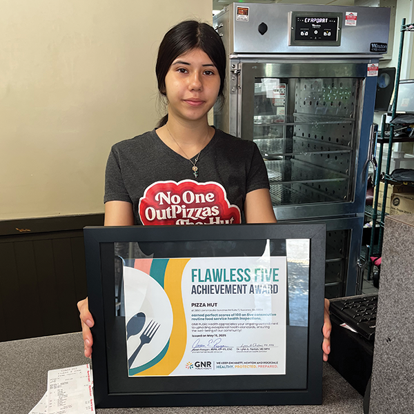 Restaurant staff poses with a framed and signed Flawless Five Achievement Award certificate.