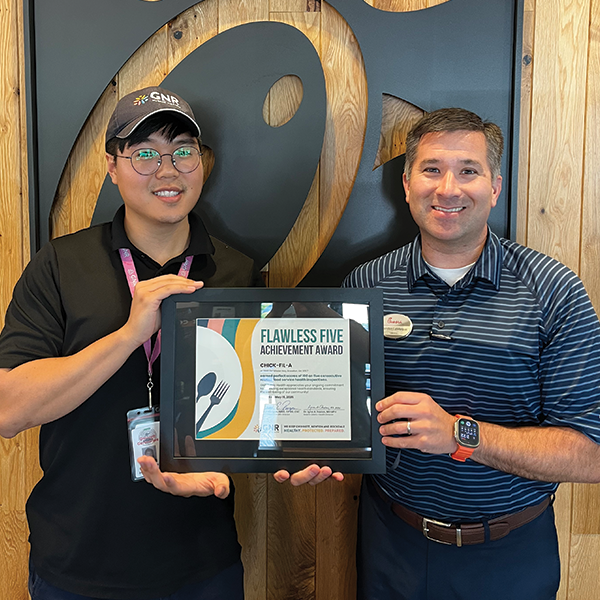 Restaurant staff and GNR Public Health inspector pose with a framed and signed Flawless Five Achievement Award certificate.