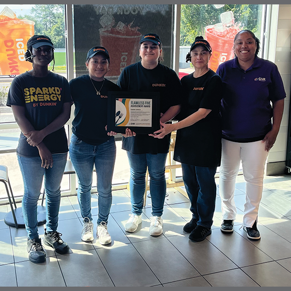 Restaurant staff and GNR Public Health inspector pose with a framed and signed Flawless Five Achievement Award certificate.