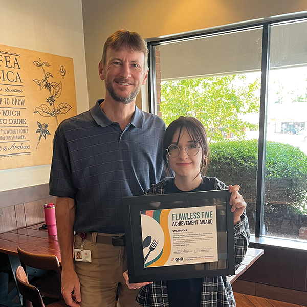 Restaurant staff and GNR Public Health inspector pose with a framed and signed Flawless Five Achievement Award certificate.