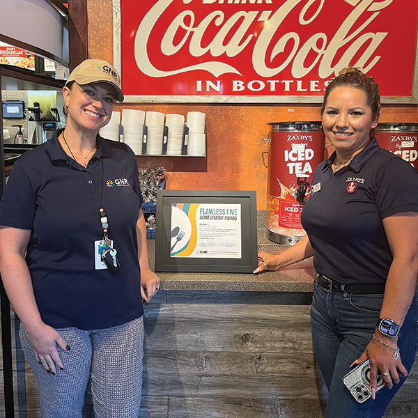 Restaurant staff and GNR Public Health inspector pose with a framed and signed Flawless Five Achievement Award certificate.