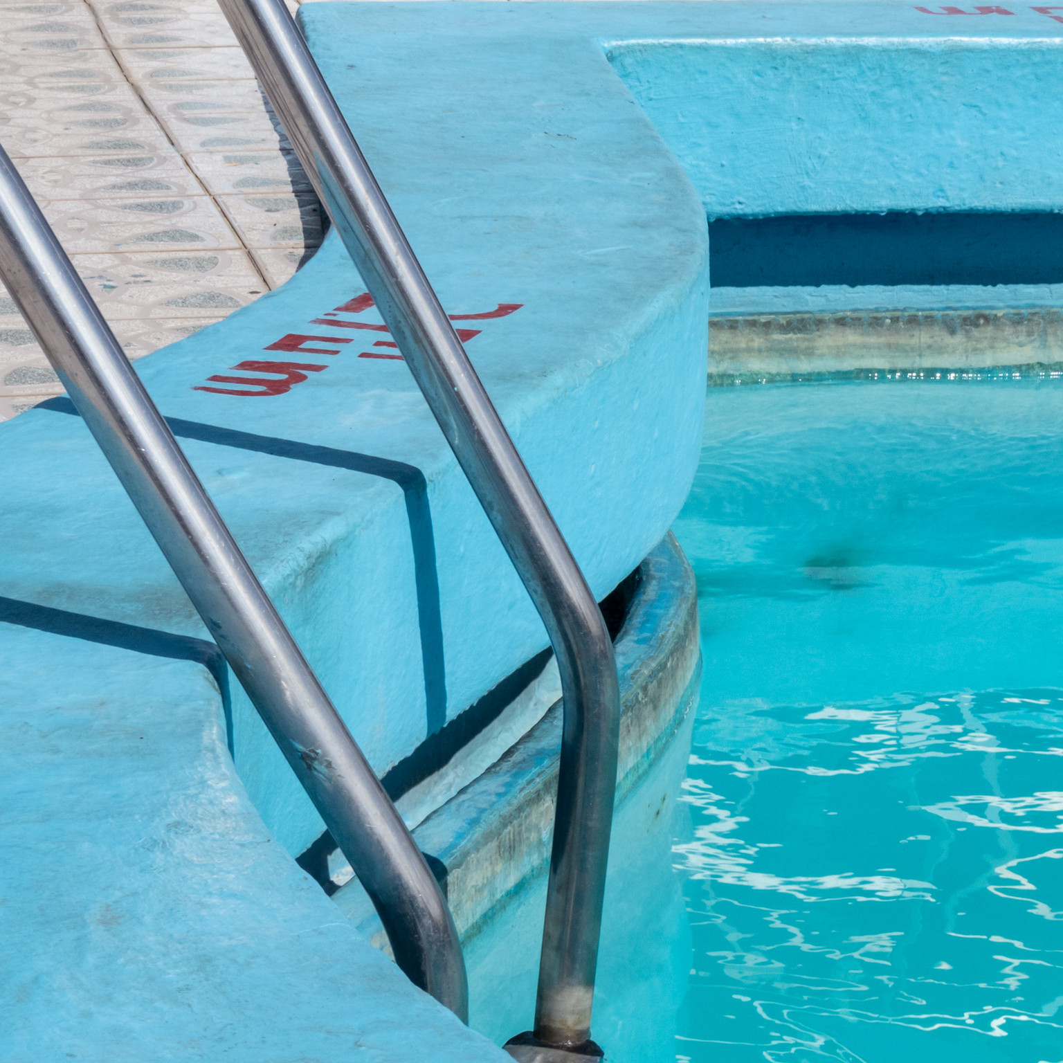 Photograph of pool ladder descending into an inground pool