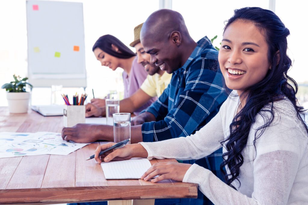 Happy businesswoman sitting with colleagues in conference room