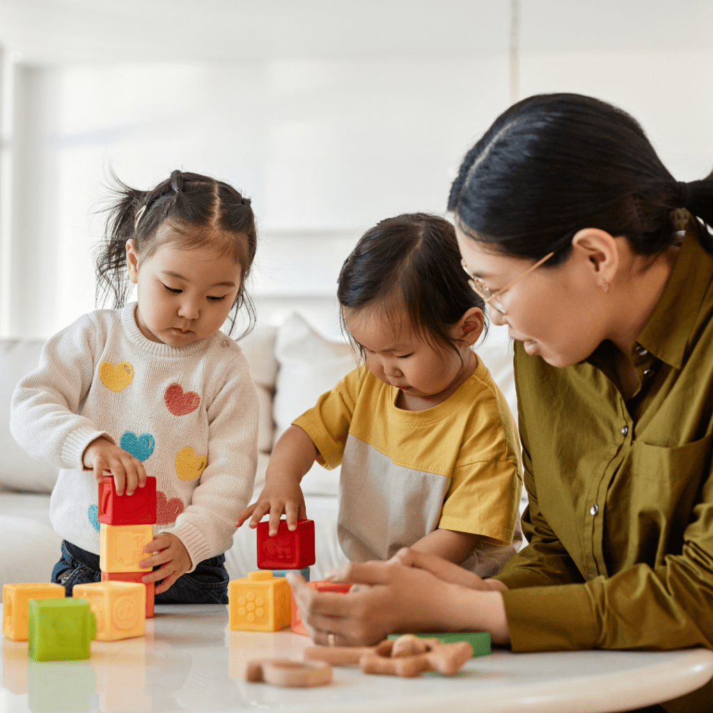 Mother and two young children playing with building blocks.