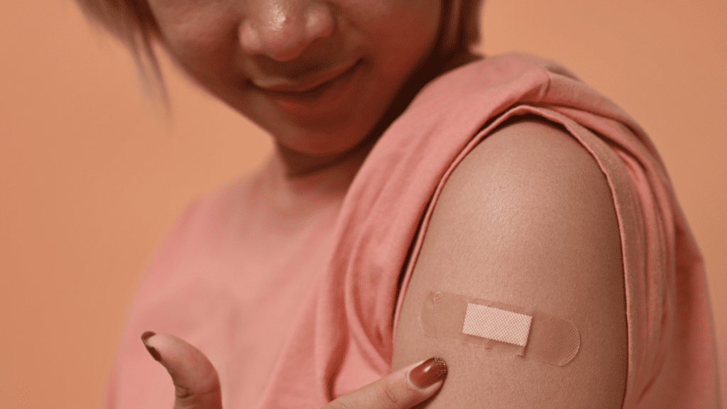 Person pointing at a band-aid on their arm.